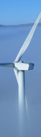 Image:  Top of a wind turbine appearing out of a foggy sky