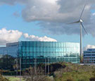 Image:  Wind turbine next to glass fronted office building