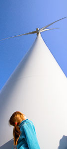 Image: Girl with red hair looking up at a wind turbine